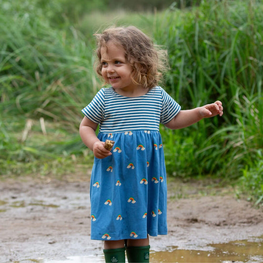 Girl wearing Little Green Radicals organic Short-sleeved dress- blue rainbows