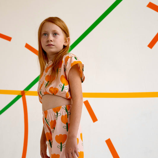 Girl wearing Don't Grow Up organic Don't Grow Up organic crop frill top- yellow flower