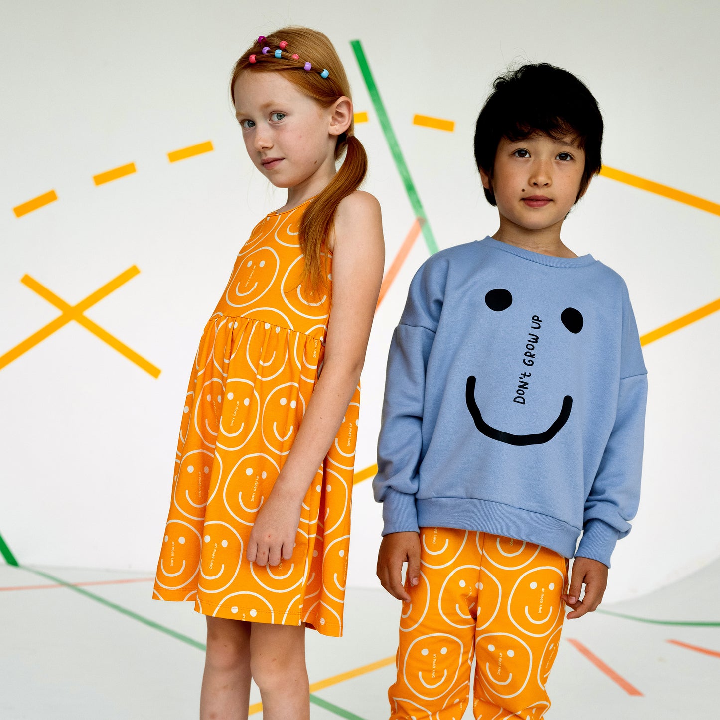 Girl wearing Don't Grow Up organic Tank dress- orange smiley