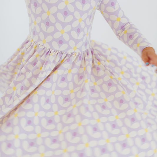 Child wearing a purple and yellow patterned dress on a white background