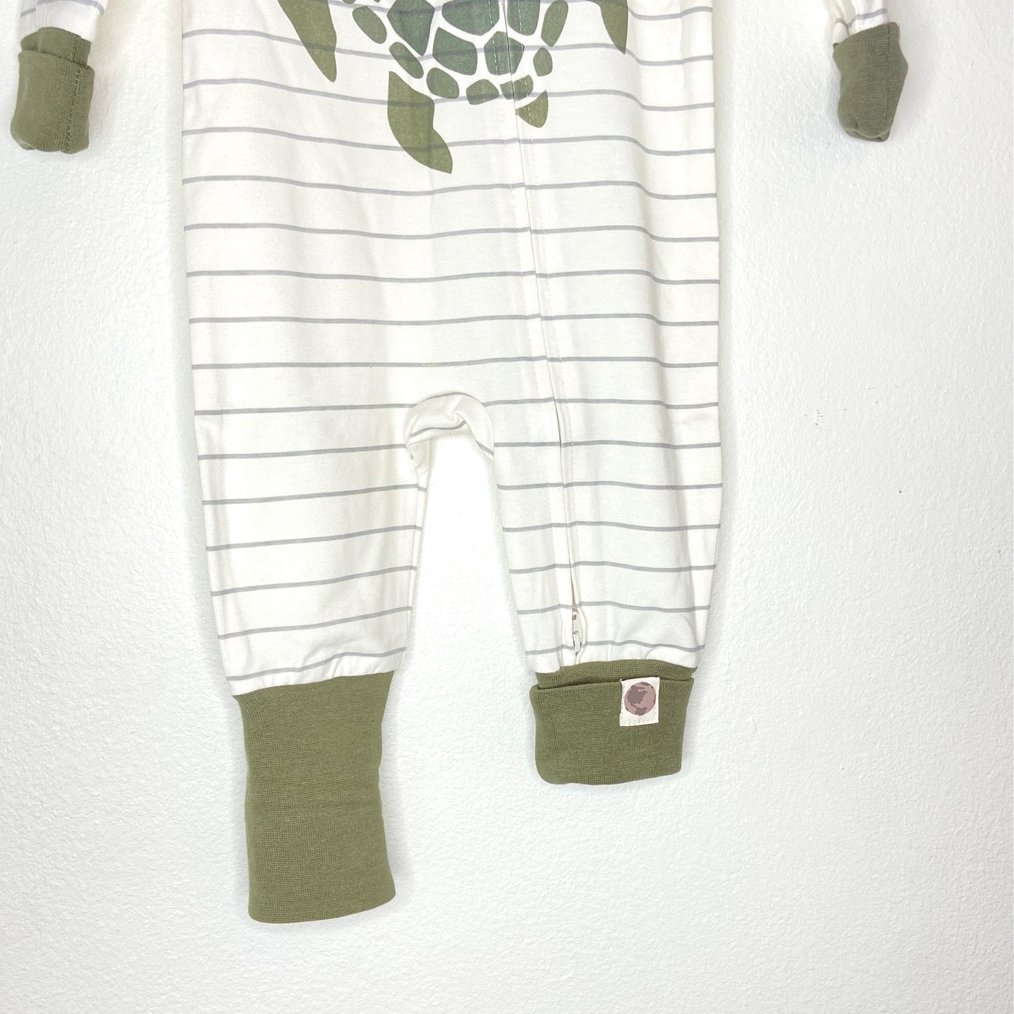 Baby onesie with turtle design and green cuffs on a white background