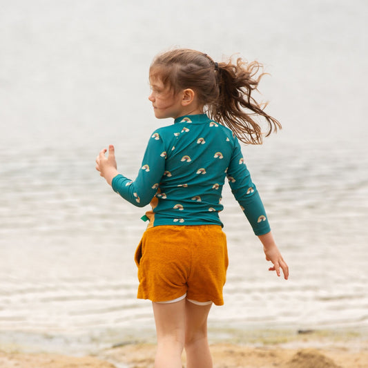 Girl wearing Little Green Radicals Recycled Rash guard- teal rainbows