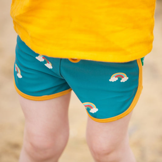 Child wearing Little Green Radicals Recycled Swim shorts- teal rainbows