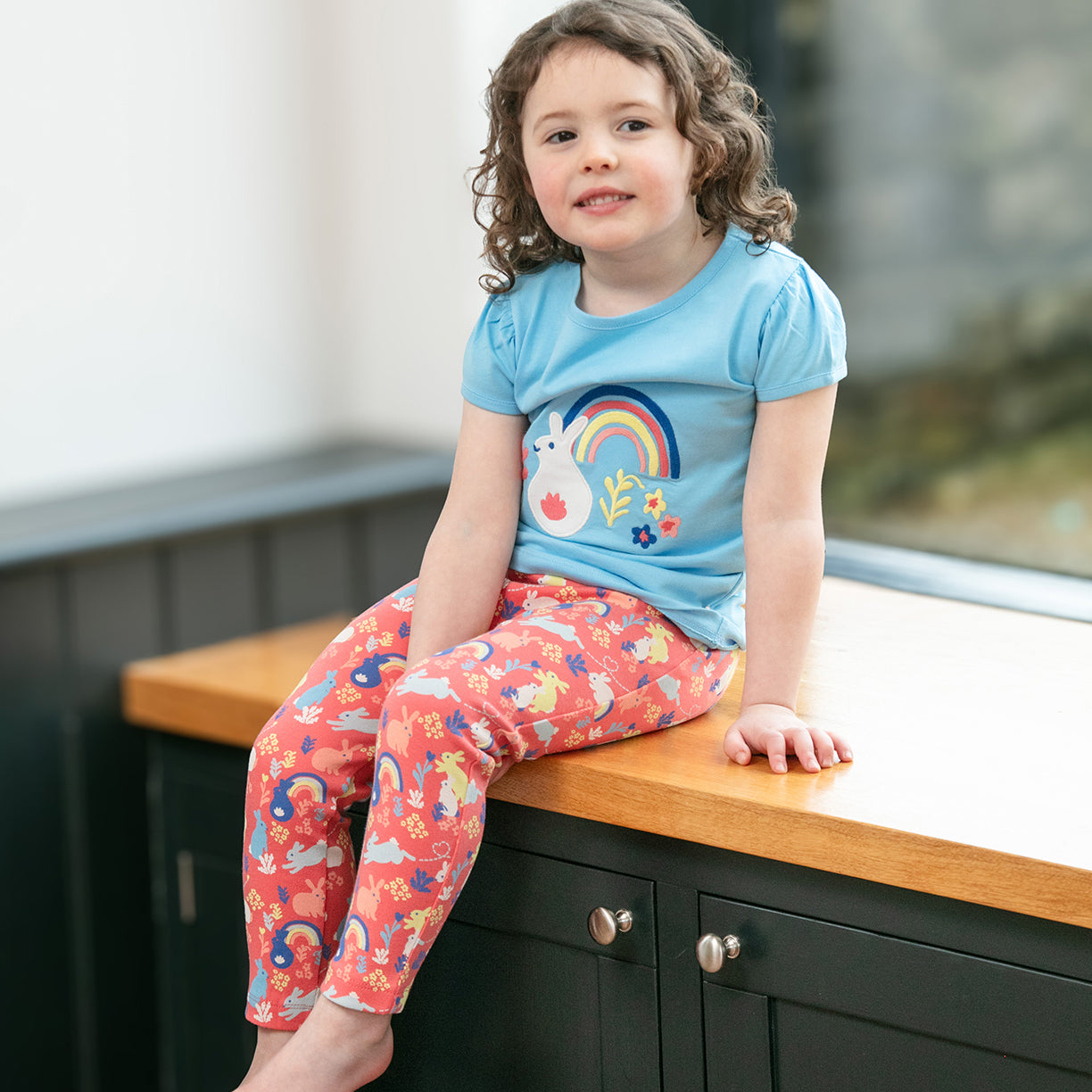 Girl wearing Piccalilly organic Short sleeve top- rainbow bunny appliqué