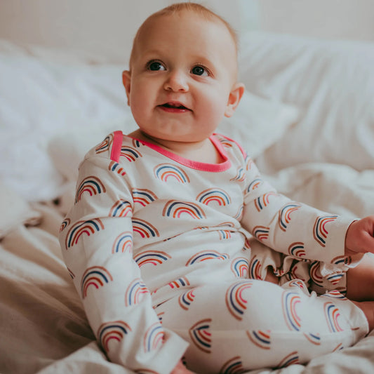 Baby wearing Lilly + Sid organic Rainbow print playsuit