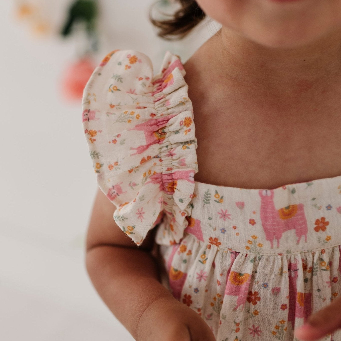 Child wearing a floral dress with llama design on a blurred background
