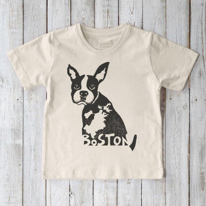 Beige t-shirt with a black dog graphic and 'Boston' text on a wooden surface
