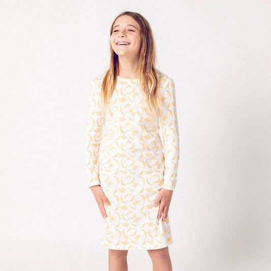 Young girl wearing a long-sleeve nightgown with a pattern on a white background