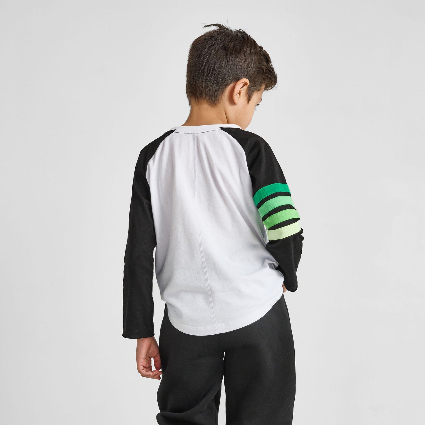 Child wearing a black, white, and green outfit on a light gray background