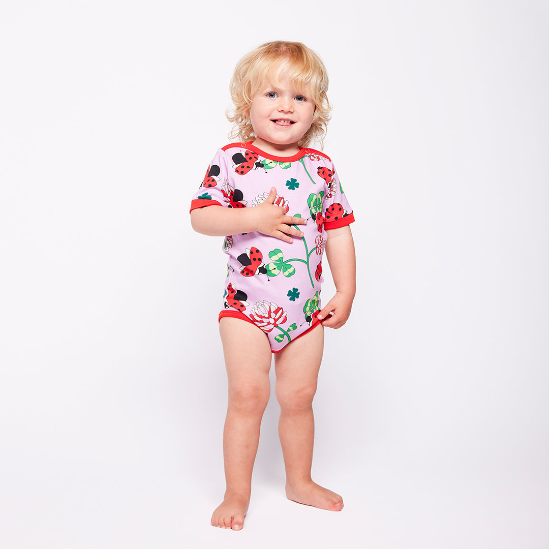 Child wearing a colorful bodysuit with ladybug design on a white background