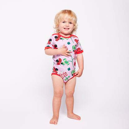 Child wearing a colorful bodysuit with ladybug design on a white background