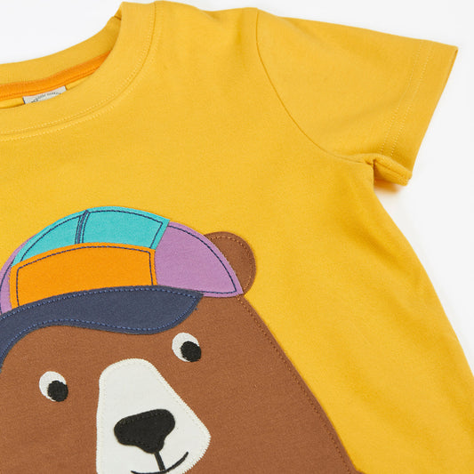 Yellow t-shirt with a bear design wearing a colorful cap on a white background