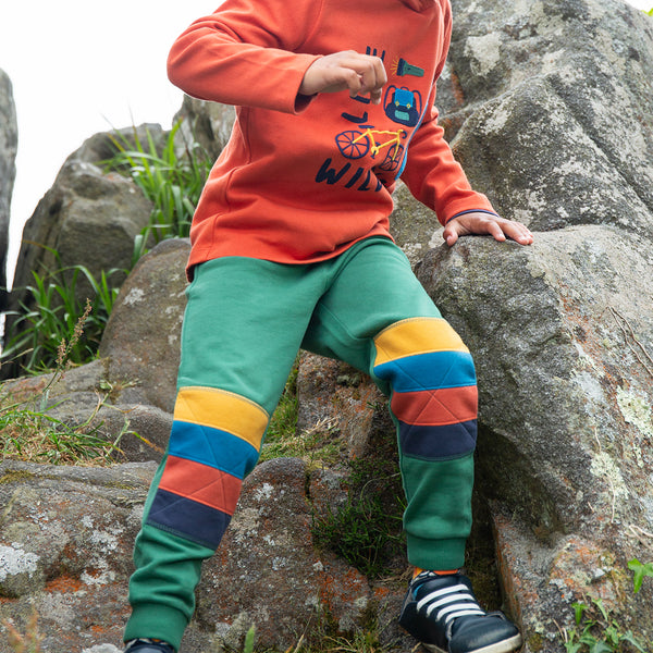 Boy wearing Frugi organic Knee patch jogger- green/rainbow