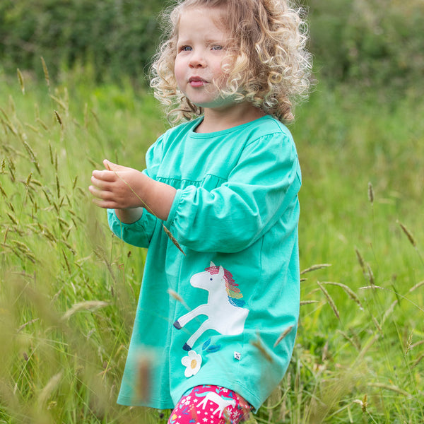 Girl wearing Frugi organic Swing top & pants set- wild horses