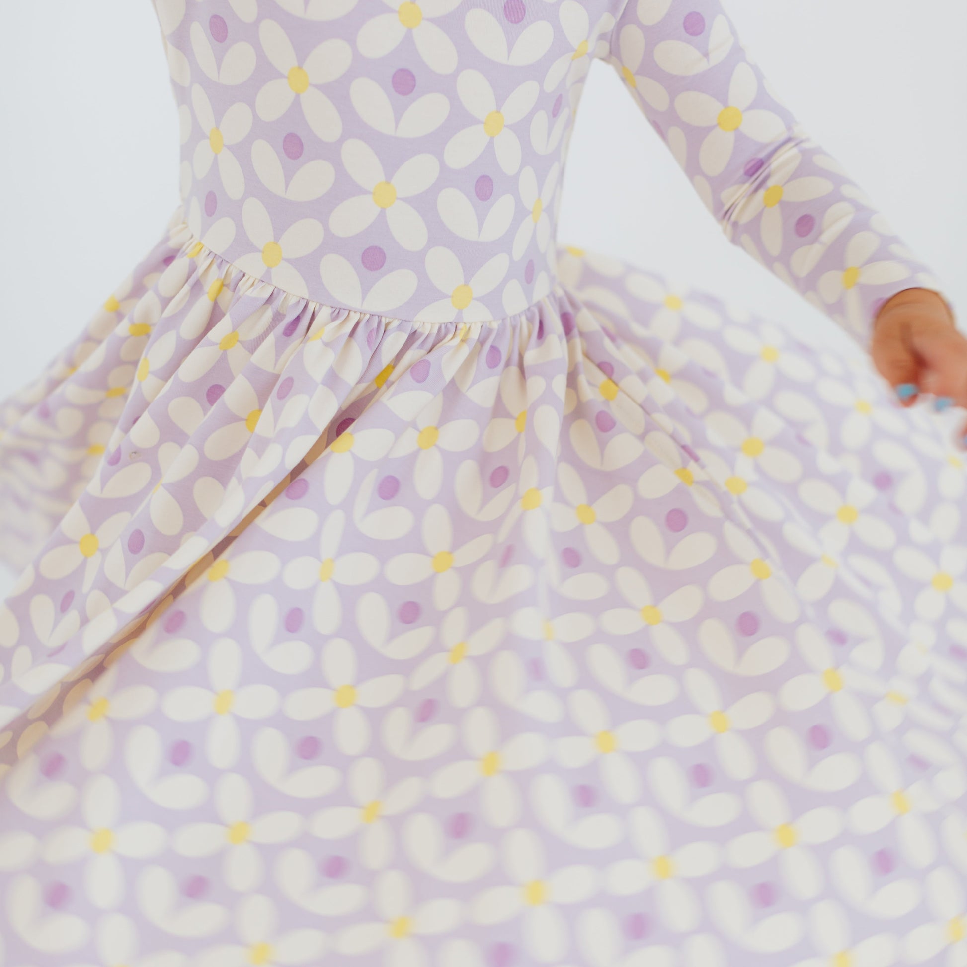 Child wearing a purple and yellow patterned dress on a white background