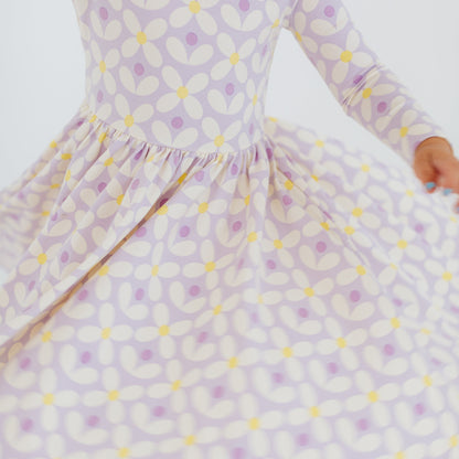 Child wearing a purple and yellow patterned dress on a white background