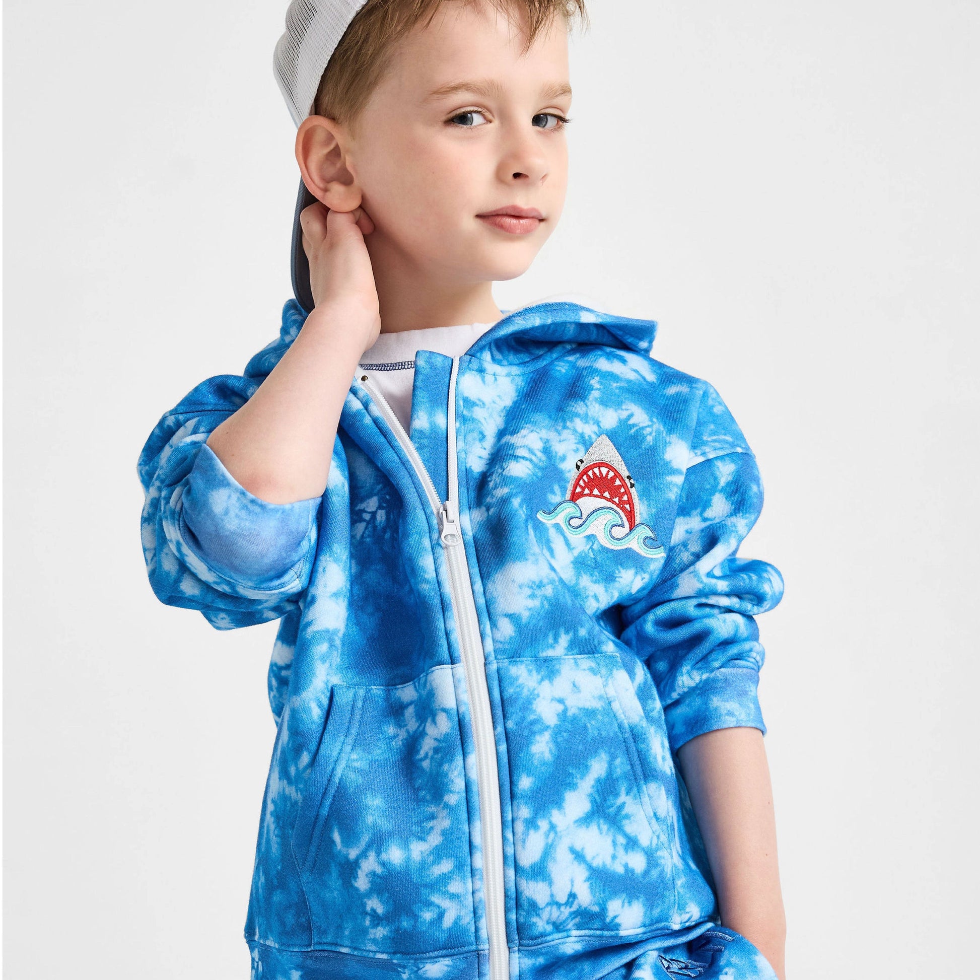 Child wearing a blue tie-dye hoodie and pants set on a white background
