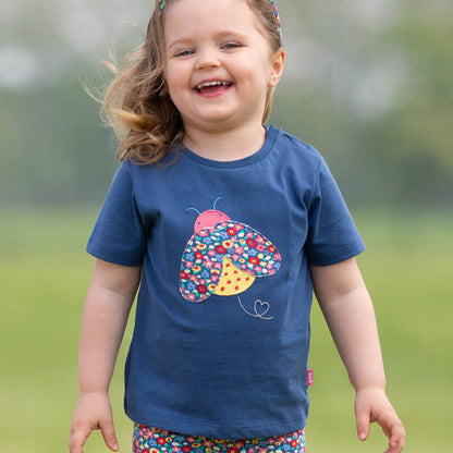 Girl wearing Kite organic T-shirt- ladybug appliqué