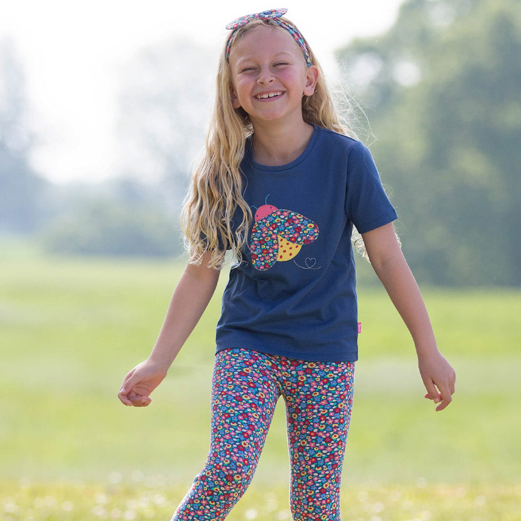 Girl wearing Kite organic T-shirt- ladybug appliqué