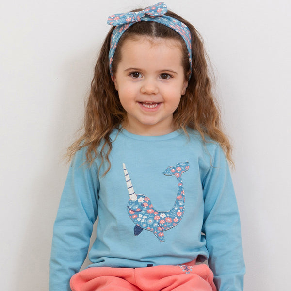 Girl wearing Kite organic T-shirt- narwhal appliqué