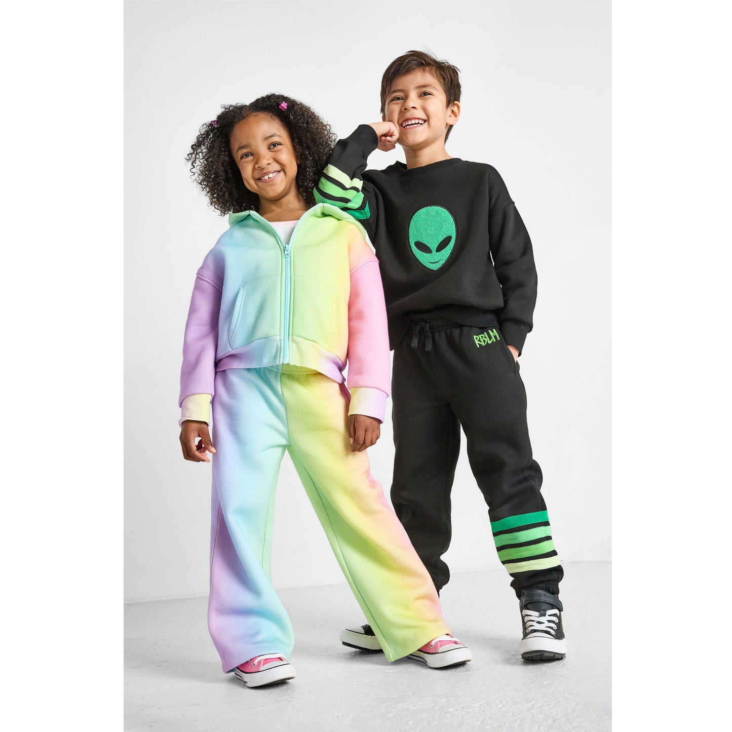 Two children wearing colorful tracksuits against a white background