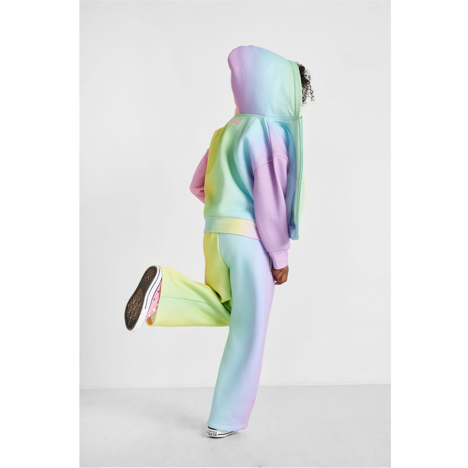 Person wearing a pastel rainbow hoodie and pants on a light gray background