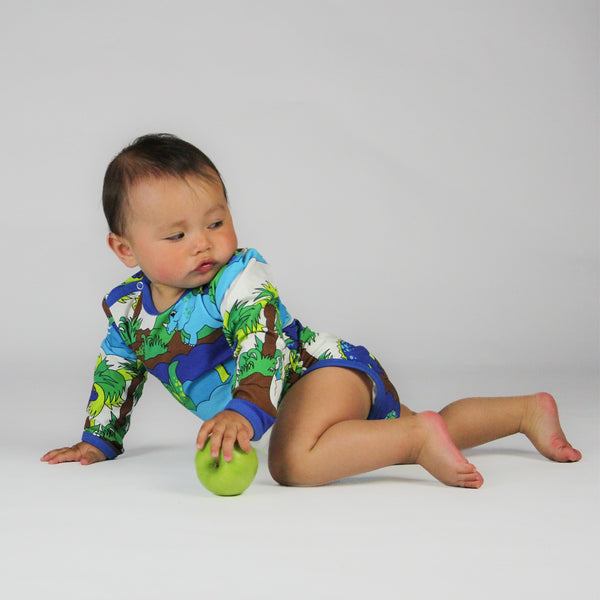 Baby wearing Smafolk organic Dinosaurs long sleeve bodysuit, blue atoll