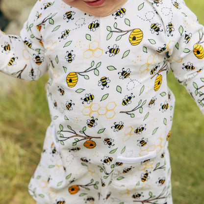 Baby wearing a onesie with bee and flower pattern outdoors
