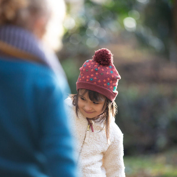 Girl wearing Little Green Radicals organic Knitted hat- hazelnut flowers