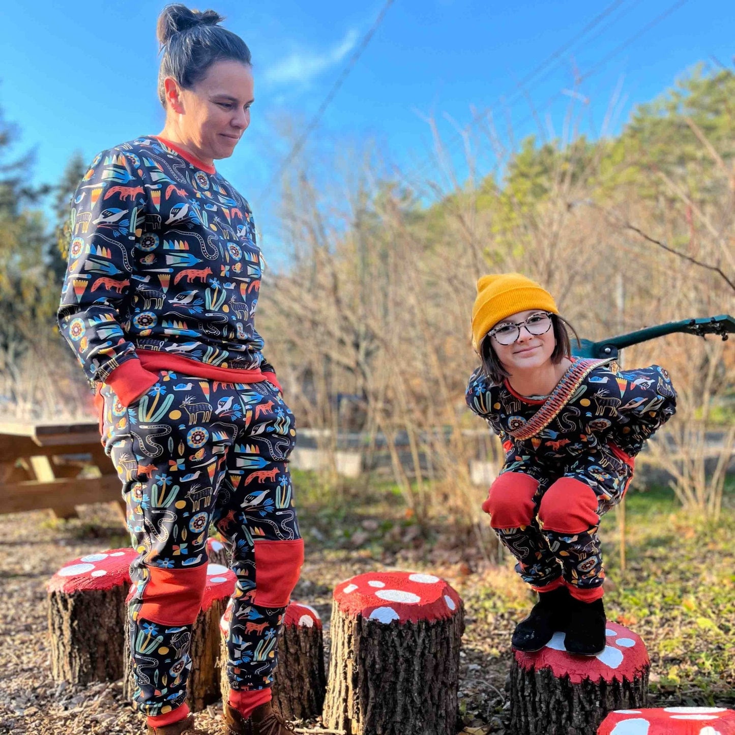 Two people wearing matching sets outdoors on wooden stools.