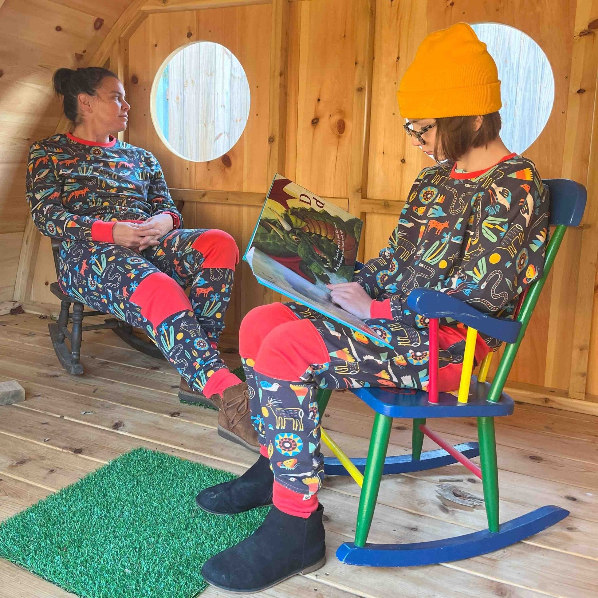 Two people in colorful sweats sitting in a wooden cabin.