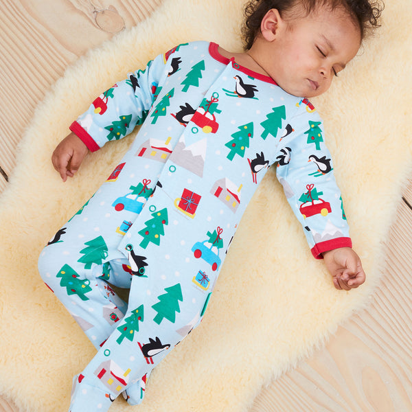 Baby wearing Toby Tiger Penguin's Christmas print footed pajamas