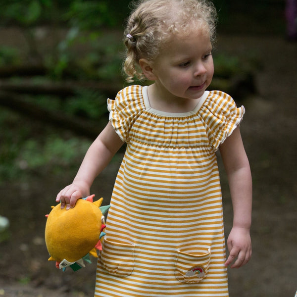 Girl wearing Little Green Radicals organic Gold striped frill dress
