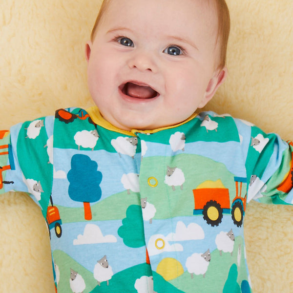 Baby wearing Toby Tiger organic Farm print footed pajamas